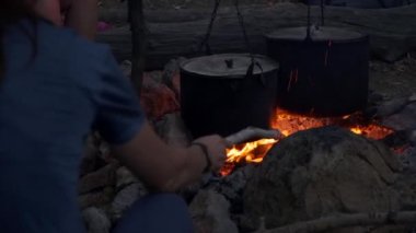 Bir kadın alacakaranlıkta kamp ateşinde esrar pişirirken yangını izliyor.. 