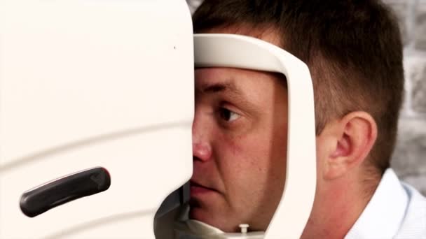 Close-up portrait of man during test on refractometer machine. — Stock Video