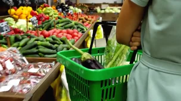 食料品店の列に沿って買い物かごを歩く女性と野菜を取る — ストック動画