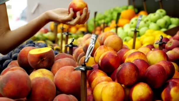 Joven mujer caucásica está eligiendo un nectarinas en el supermercado — Vídeos de Stock