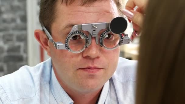 En mand, der har foretaget en øjenundersøgelse af optiker. Valg af korrekte linser – Stock-video
