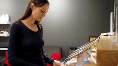 Genç bir kadın elektronik mağazasında yeni bir akıllı telefon seçiyor..