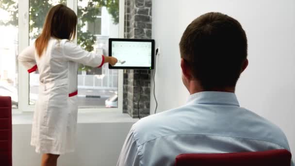 Teste de visão no salão de óptica. Homem lê símbolos na tela do monitor — Vídeo de Stock