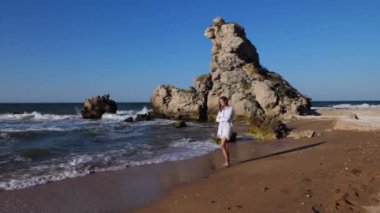 Genç ve çekici bir kadın sahilde yalnız yürüyor..