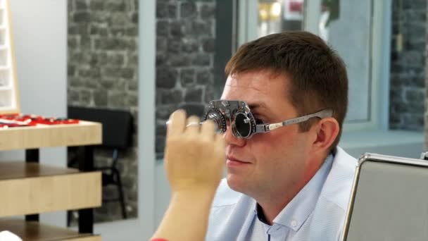 Homem tenta óculos de visão com lentes diferentes para determinar óculos adequados. — Vídeo de Stock