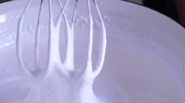 Elektrikli mikser küçük bir fincanda kalın bir sos kırbaçlıyor.