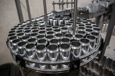Bira fabrikasında bira şişeleme teknolojisi. Boş alüminyum bira kutuları taşıyıcı bant boyunca hareket ediyor. Temiz bira şişeleri taşıyıcı boyunca hareket ediyor. Endüstri, üretim hattı, kapatın..