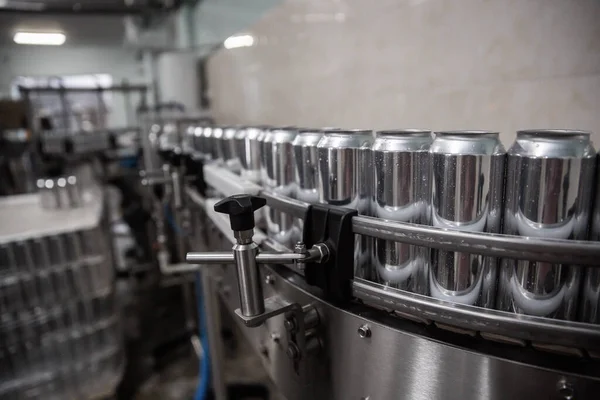 Technological line for bottling of beer in brewery. Empty aluminum beer cans are moving along the conveyor belt. Clean beer bottles are moving along the conveyor.Industry, production line, close up.