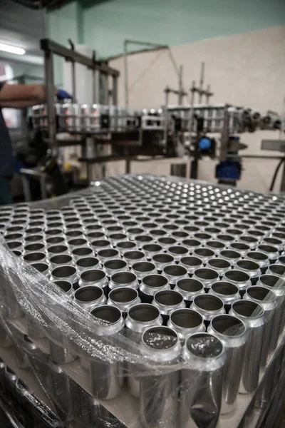 Technological line for bottling of beer in brewery. Empty aluminum beer cans are moving along the conveyor belt. Clean beer bottles are moving along the conveyor.Industry, production line, close up.