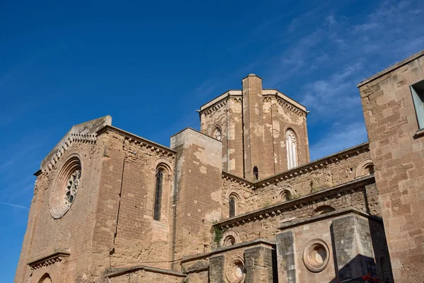 Eski altın kumtaşı duvarlarıyla Lleida 'daki görkemli La Seu Vella Katedrali çerçeveye hükmediyor. Düşük açılı çekim, binanın kemerli pencereler, bir gül penceresi gibi heybetli ölçekli ve mimari ayrıntılarını vurguluyor