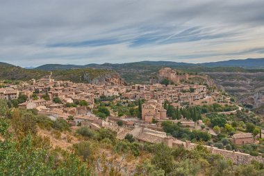 Huesca ilindeki bir ortaçağ İspanyol köyü olan Alquezar 'ın panoramik manzarası, sıcak tonlu taş evleri ve kayalık yamaçlar boyunca uzanan kil çatıları. Kompozisyon, tepenin üstündeki eski şatoyu ve kolej kilisesini ele geçiriyor.