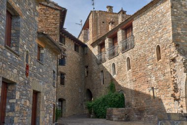Dar taştan caddelerin arasında Ainsa kilisesinin Romen kulesi duruyor ve bu Huesca köyünün ortaçağ karakterini vurguluyor. Taşın ılık tonları, çiçeklerle dolu balkonlar ve mavi gökyüzü tarihi, özgünlüğü aktarıyor.