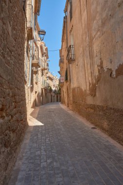 Dar sokakların özü ve Calaceite köyünün taş mimarisi. Görüntüler, mavi gökyüzünün altındaki kaldırım taşlarından, tarihi kemer ve merdivenlerin detaylarına kadar uzanan farklı perspektifleri gösteriyor.. 