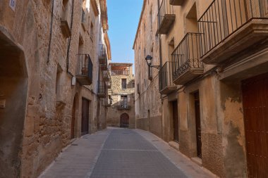 Dar sokakların özü ve Calaceite köyünün taş mimarisi. Görüntüler, mavi gökyüzünün altındaki kaldırım taşlarından, tarihi kemer ve merdivenlerin detaylarına kadar uzanan farklı perspektifleri gösteriyor.. 