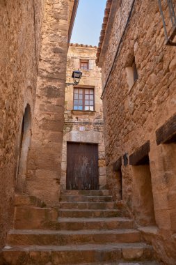 Dar sokakların özü ve Calaceite köyünün taş mimarisi. Görüntüler, mavi gökyüzünün altındaki kaldırım taşlarından, tarihi kemer ve merdivenlerin detaylarına kadar uzanan farklı perspektifleri gösteriyor.. 
