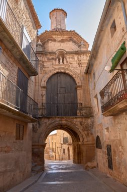 Heybetli Orca Kapısı ve Calaceite 'deki San Antonio Hermitage taş kemerleri ve Barok cephesiyle. Resimlerin bileşimi dikeylik ve mimari ayrıntıları vurgular