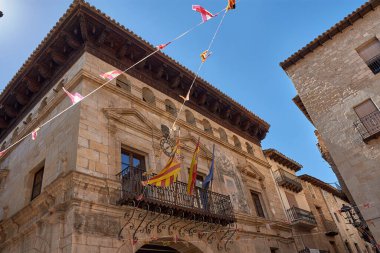 Valderrobres belediye binasının görkemli cephesi Teruel, Rönesans mimarisinin muhteşem bir örneği. Güneş ışığı kireç taşına düşer, işlenmiş demir balkonlarının ayrıntılı detaylarını vurgular, oyulmuş arma arması. 