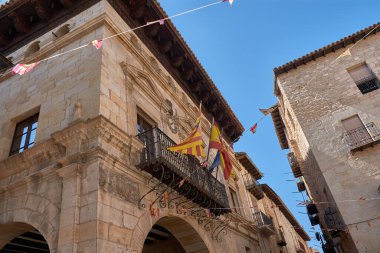 Valderrobres belediye binasının görkemli cephesi Teruel, Rönesans mimarisinin muhteşem bir örneği. Güneş ışığı kireç taşına düşer, işlenmiş demir balkonlarının ayrıntılı detaylarını vurgular, oyulmuş arma arması. 