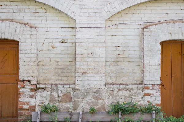 İki büyük kahverengi ahşap kapı eski beyaz bir duvar üzerinde