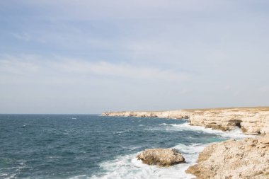 Deniz dalgaları kayalara çarpıyor. Gün