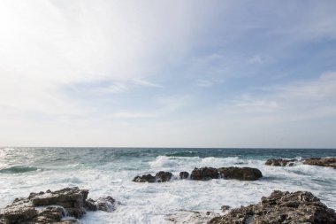 Deniz dalgaları kayalara çarpıyor. Gün