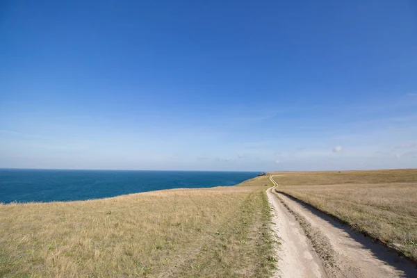 Grote stenen kalme zee, heldere hemel met wolken skyline en weg Rechtenvrije Stockfoto's