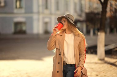 Genç kadın kahverengi palto ve şapka açık havada kahve içme