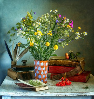 kitap, kağıt ağırlığı, tüyler, alan çiçekler, rowan ve elma ile natürmort. Vintage.