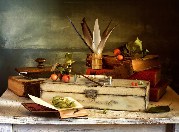 a still life with books, a box of feathers, and a paperweight. vintage. retro.