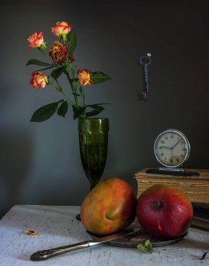 mango meyve, kitap ve bir buket gül ile natürmort. Vintage.