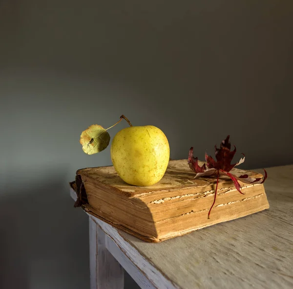 Still life with a book, an apple and a maple leaf. vintage