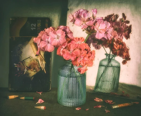 Still life with geranium flowers and pencils. An interesting reflection of colors. Vintage. Retro.