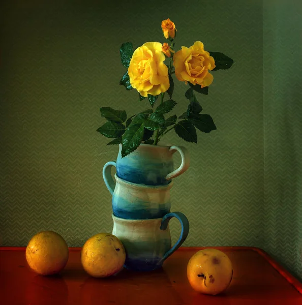 A bouquet of roses in a vase of cups and yellow plums on the table. Still life. Vintage.