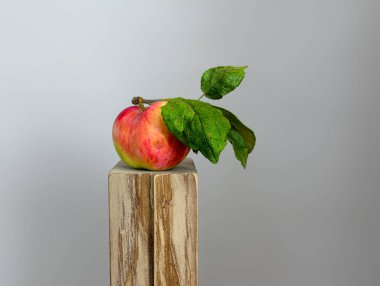 Tahta bir blokta yeşil yapraklı olgun ve güzel bir elma. Durgun hayat. Minimalizm.