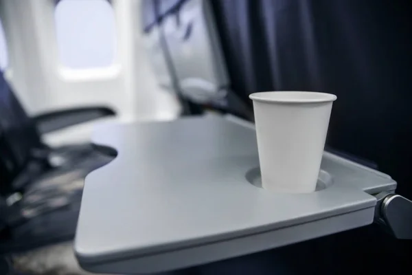 Taza de plástico sobre la mesa en el avión durante el vuelo. consumo de alcohol a bordo — Foto de Stock