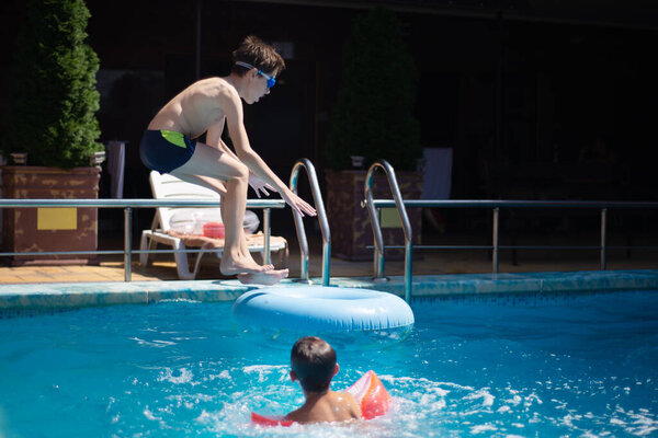 Blured image of child jumping at swimming pool party - Vacation concept with happy friends having fun in summer day at leisure aquapark. No focus.