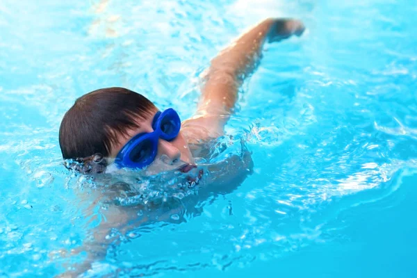 Gezicht zwemmer atleet in glazen close-up in druppels water. Kleine jongen atleet zwemt in het zwembad bij het kruipen. Het concept sport en gezonde levensstijl. — Stockfoto