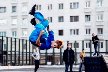 Norilsk, Rusya - 28 Ağustos 2016: Genç atlıyor ve takla atıyor. Sokaktaki Parkour.
