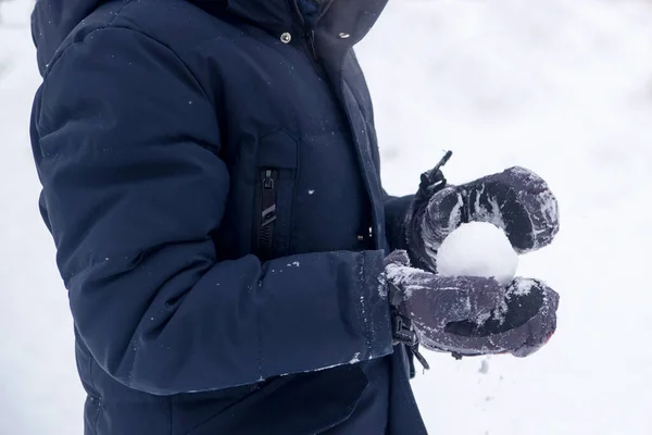 Osoba trzymająca kulę śnieżną. Zbliżenie przyciętych rąk trzymając śnieżkę. — Zdjęcie stockowe