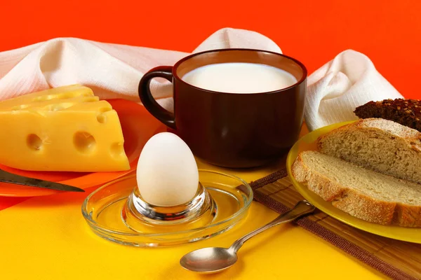 鶏の卵 チーズ ミルク 黄色とオレンジ色の背景にパンのマグカップのある静物 — ストック写真