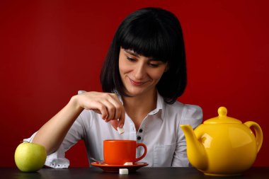 Gülümseyen kız portresi ile fincan çay, şeker ve su ısıtıcısı Bordo arka plan üzerinde