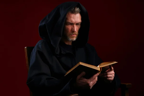 Medieval monk in a black robe with a book in his hands