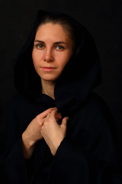 Young woman in a black cloak with a hood