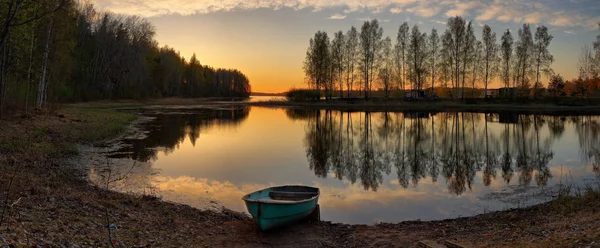 Abendpanorama mit einem Fischerboot am Ufer eines ruhigen Sees — Stockfoto