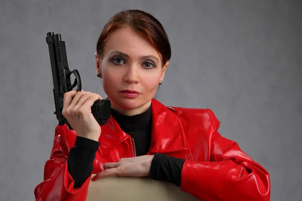 Retrato de una mujer con una chaqueta roja con un arma — Foto de Stock