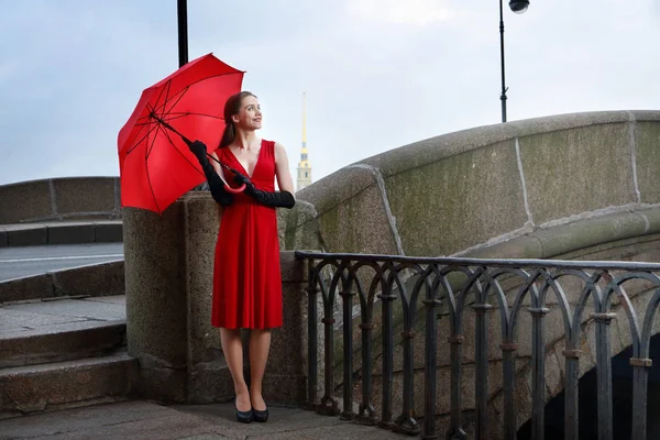 Το κορίτσι με το κόκκινο φόρεμα στο φόντο της γέφυρας του ερημητήριο στο — Φωτογραφία Αρχείου