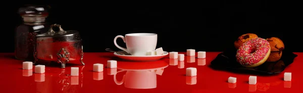 Panorama with a Cup of coffee, a donut and sugar on a red glossy