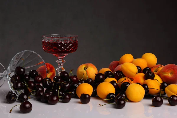 Copa de vino, cerezas, albaricoques y melocotones — Foto de Stock