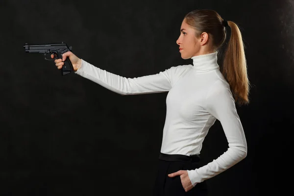 Chica delgada con pistola sobre fondo oscuro — Foto de Stock