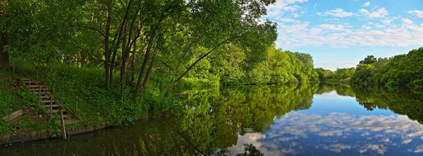 La vista desde el espejo-río con escalones de madera en el agua — Foto de Stock